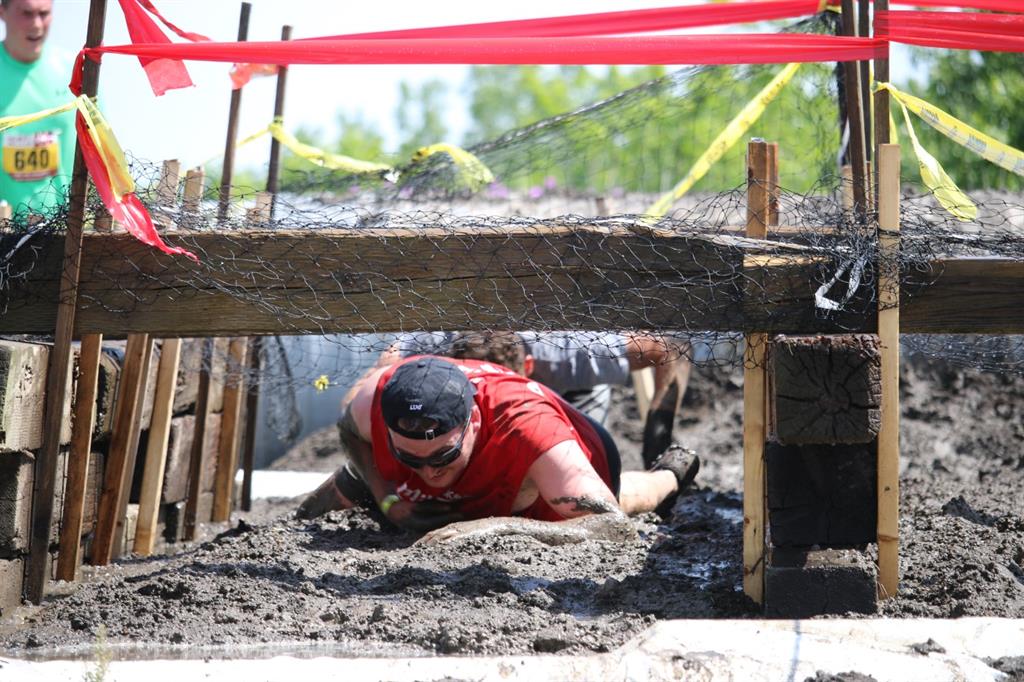 Person crawling through a muddy obstacle